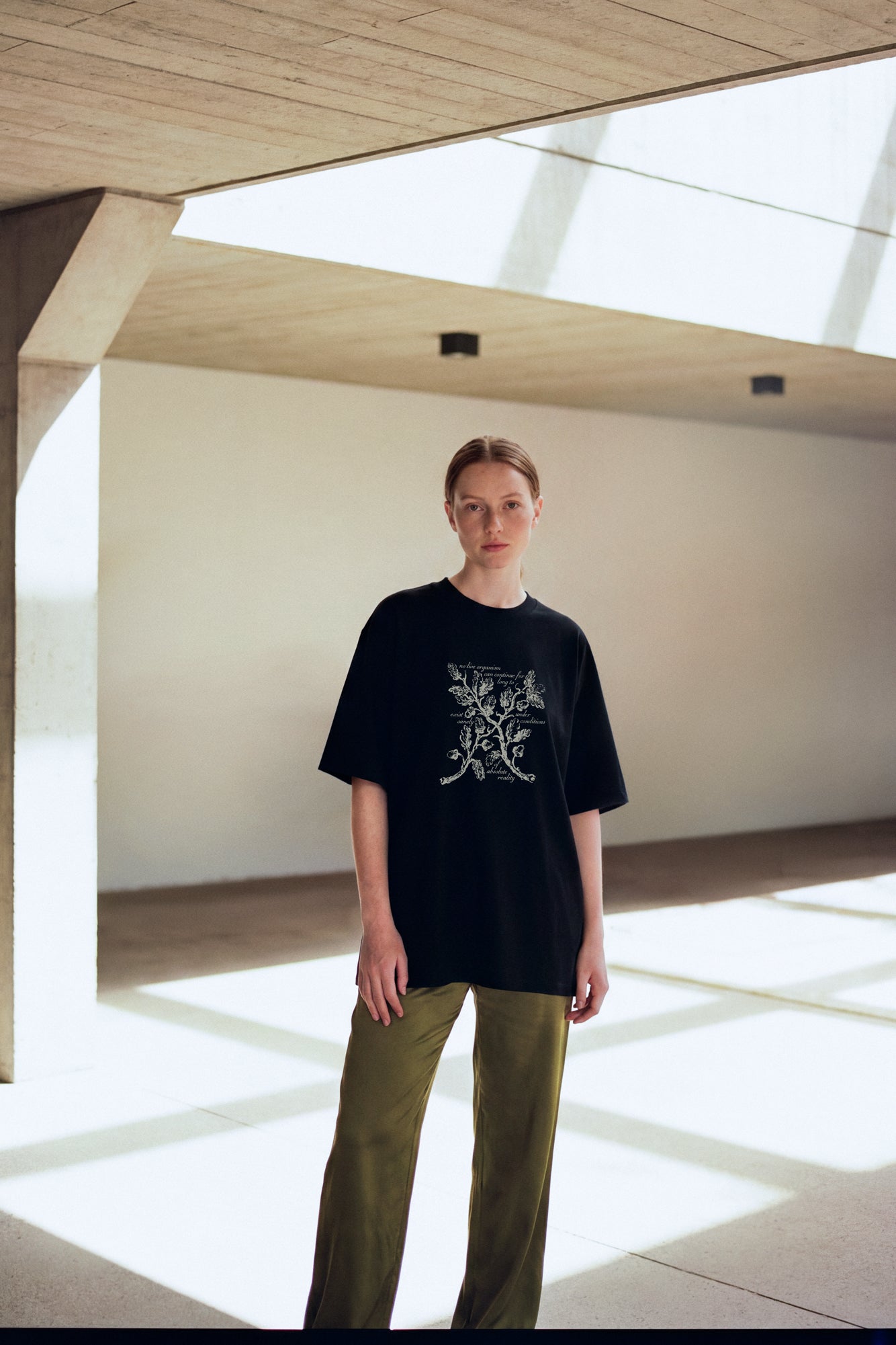 Person wearing a black t-shirt with a floral design and and a Haunting of Hill House by Shirley Jackson quote in a modern indoor setting