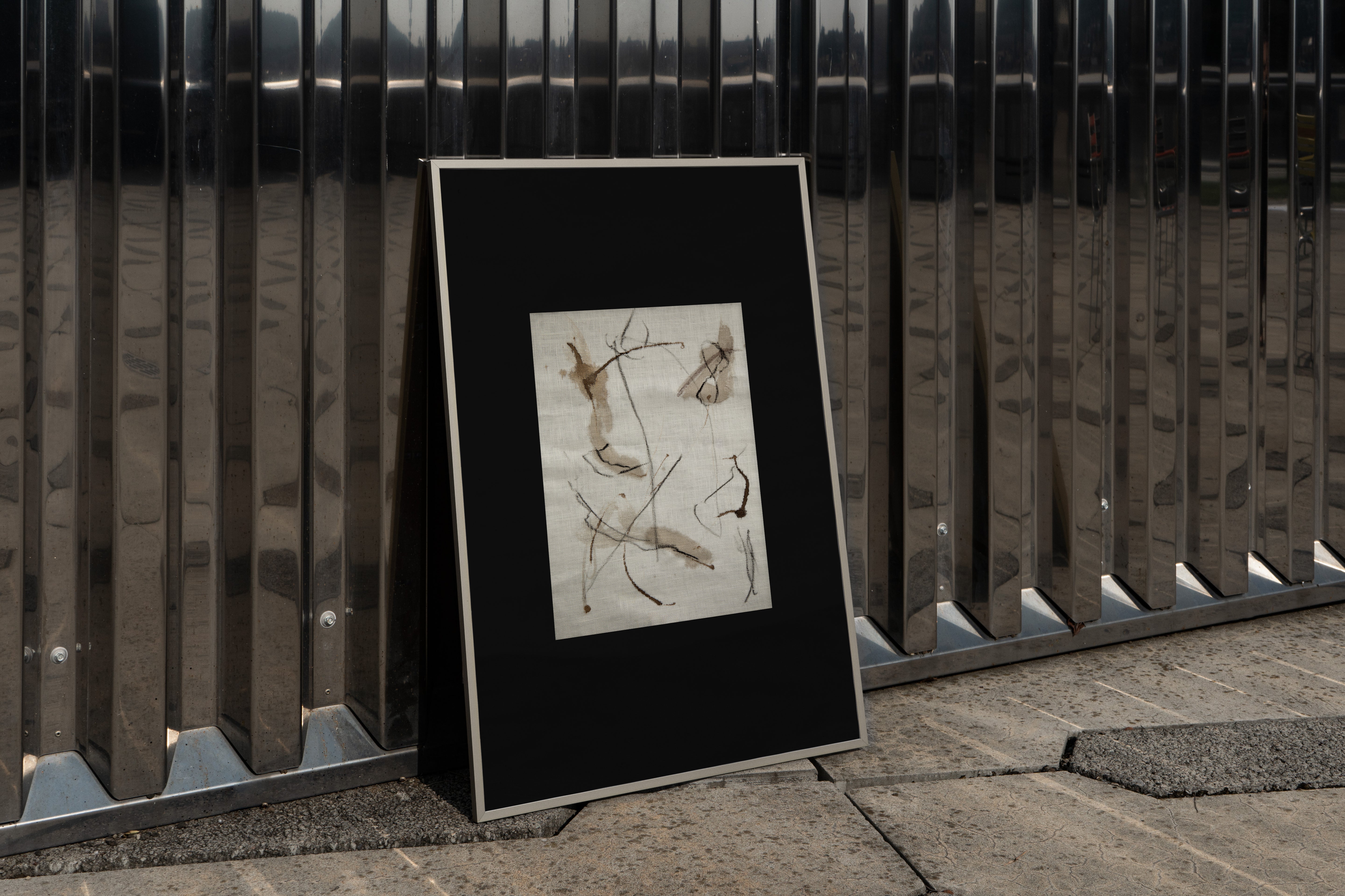 Framed artwork leaning against a metal fence