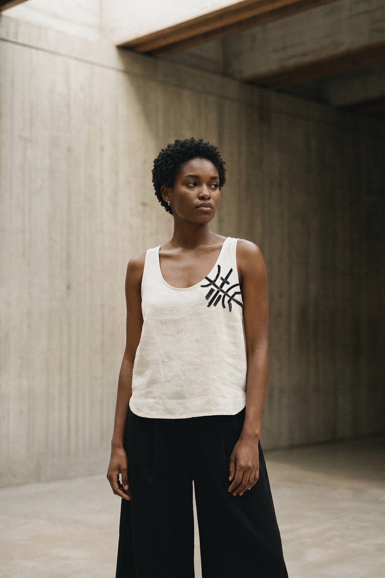 Woman standing in a hand painted custom linen tank top. Original artwork and clothing by Sara Kraus, Double Kick, alternative, small-batch, made-to-order, linen, artistic apparel and designs.