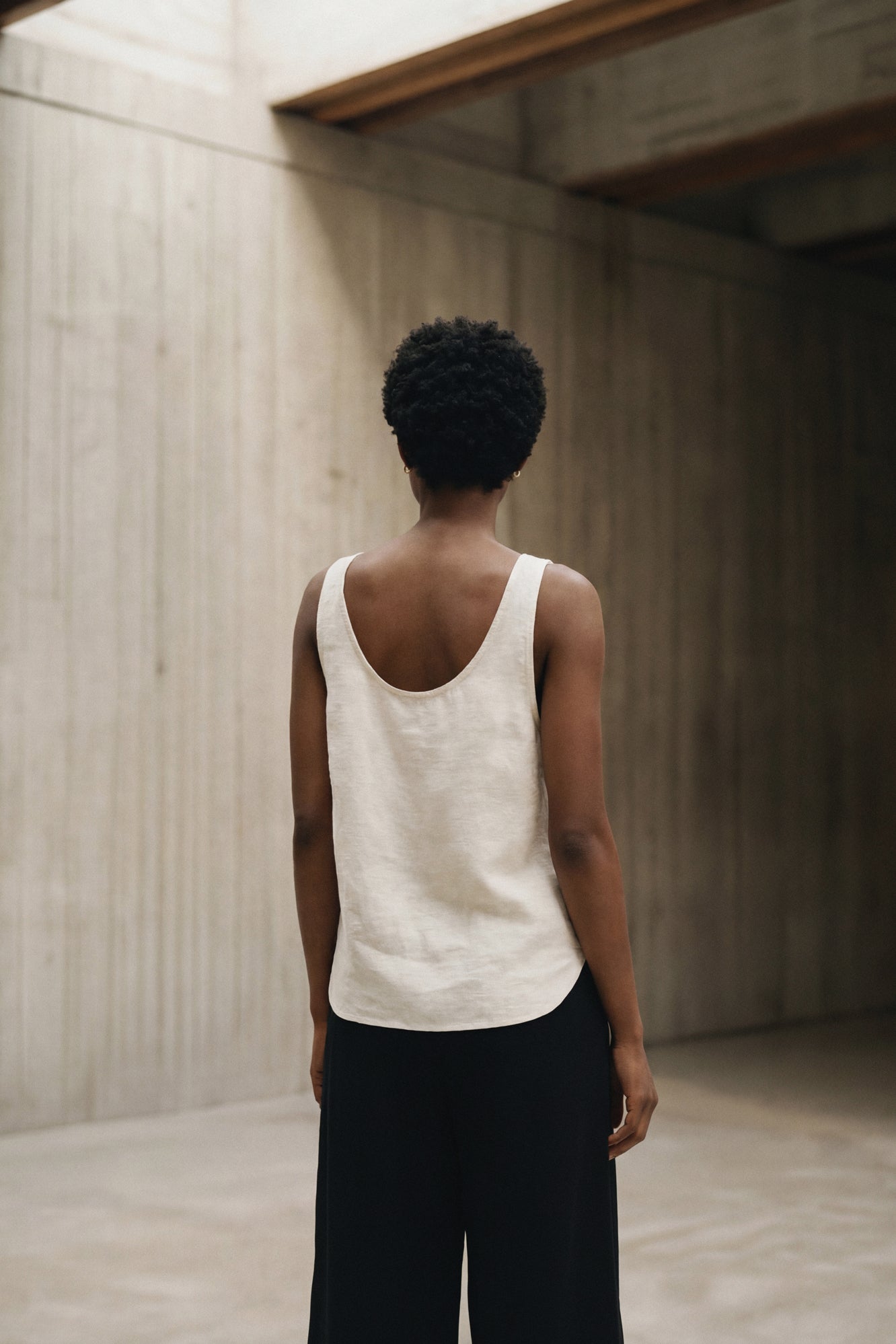 Woman standing in a hand painted custom linen tank top. Original artwork and clothing by Sara Kraus, Double Kick, alternative, small-batch, made-to-order, linen, artistic apparel and designs.