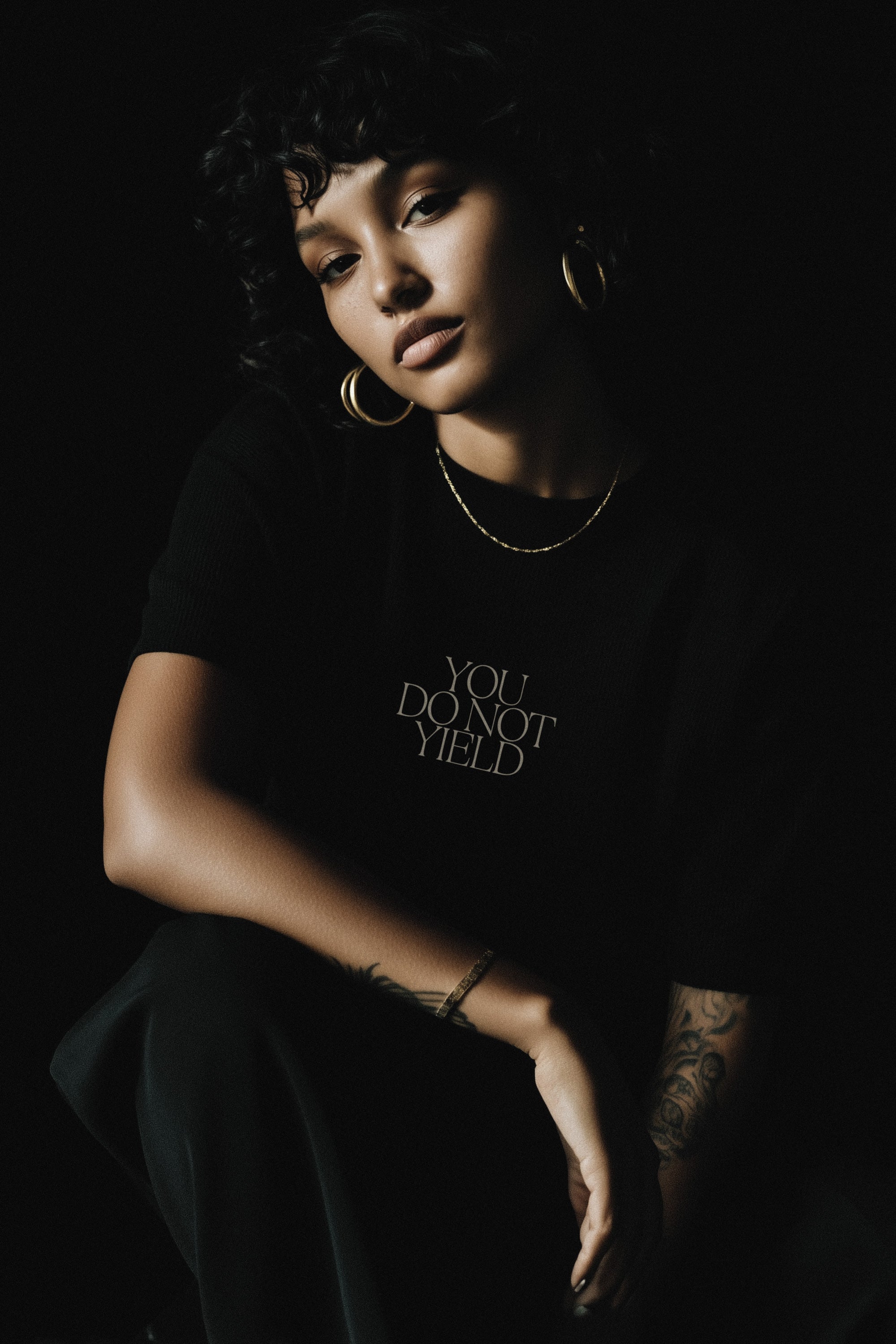Person wearing a black t-shirt with 'YOU DO NOT YIELD' text on a dark background