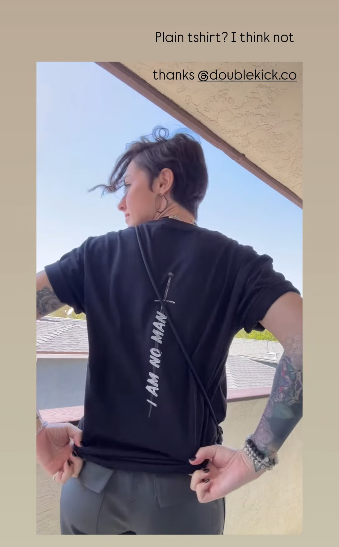 Person wearing a black t-shirt with text, standing outdoors.