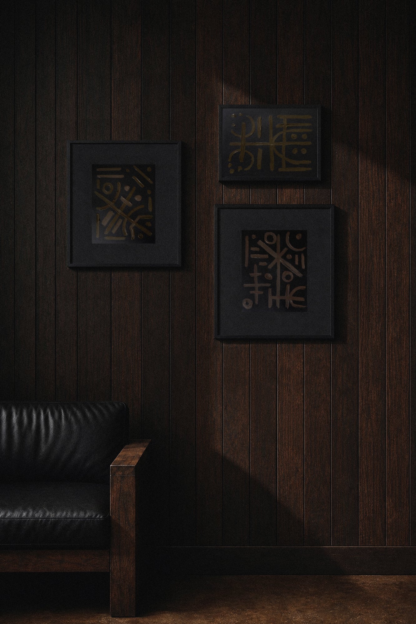 Dark wooden wall with decorative framed artwork and original paintings and a black leather chair.